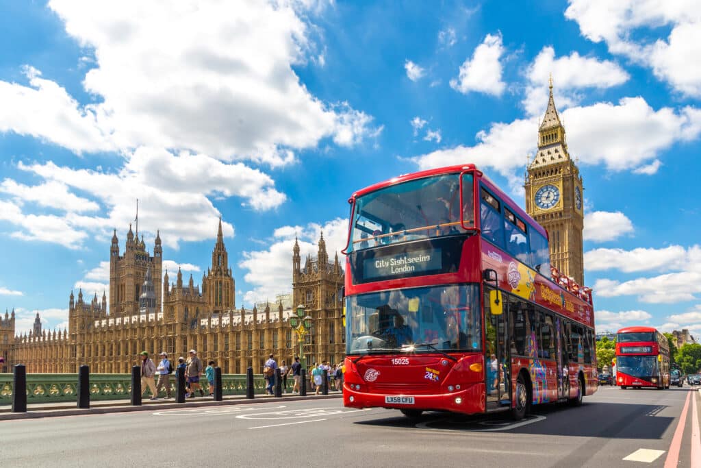 Open-top Hop-on Hop-off Bus; City Sightseeing on Westminster Bridge with Big Ben and Palace of Westminster behind.
