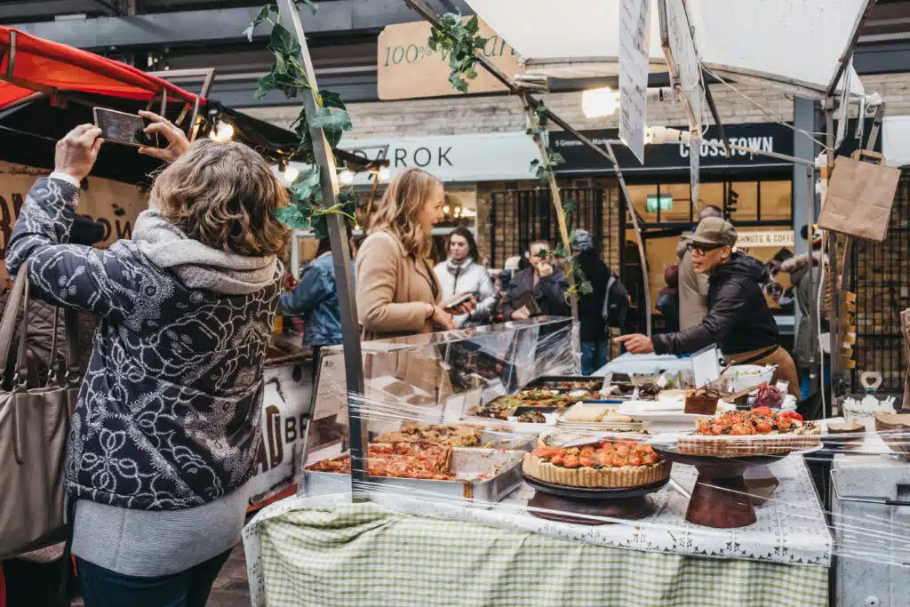 A Guide to Greenwich Market Woman buying cakes from a market stall at Greenwich Market, London